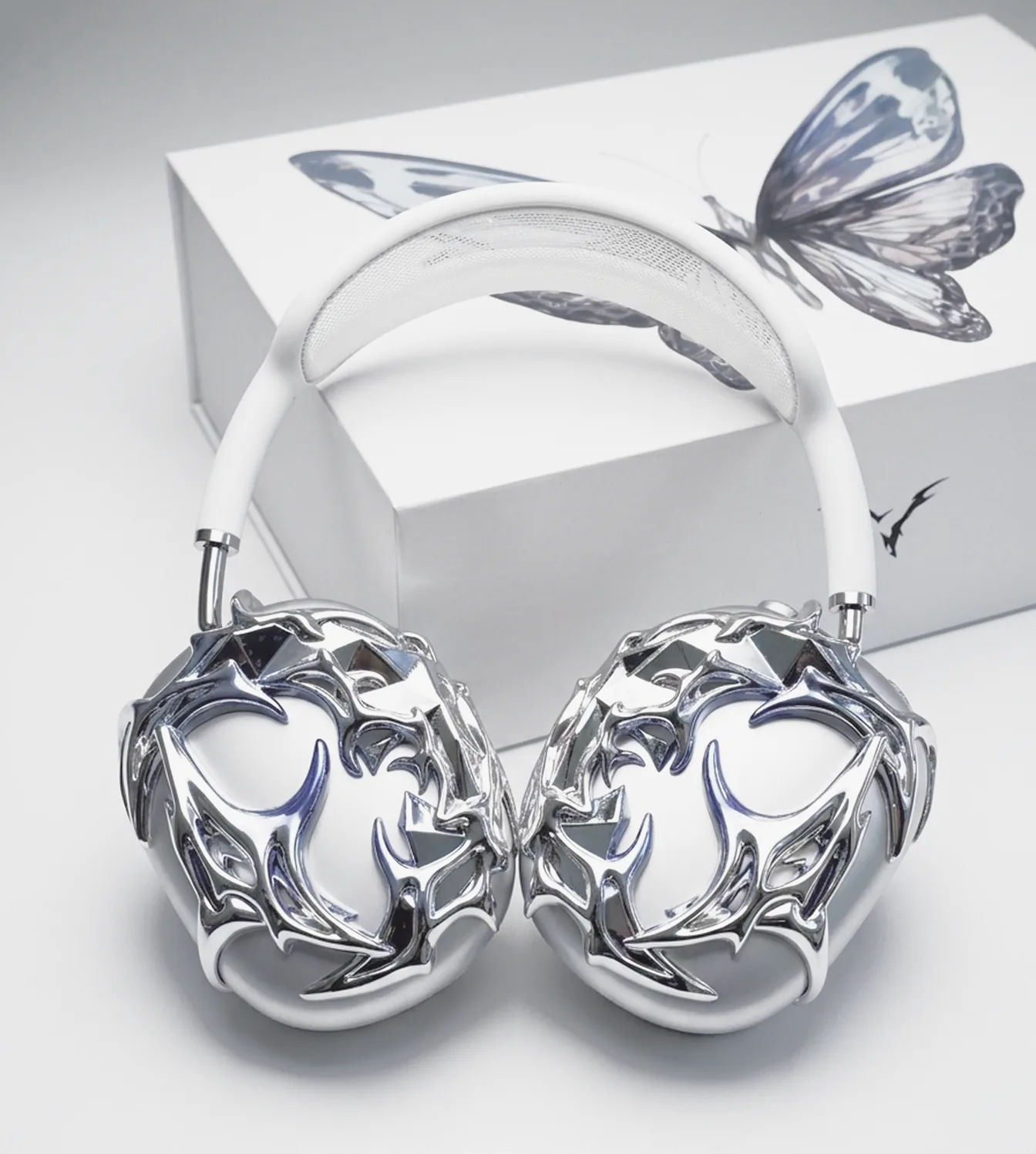 A matched pair of chrome thorn pieces on white headphones, box behind